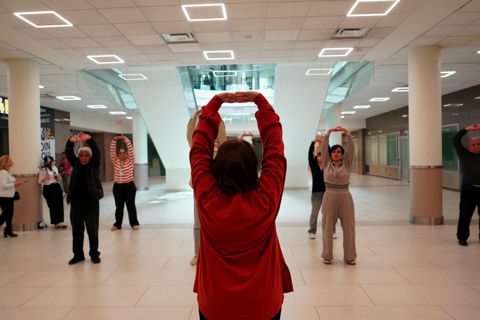 A group of older adults practising tai chi indoors for balance and mobility.